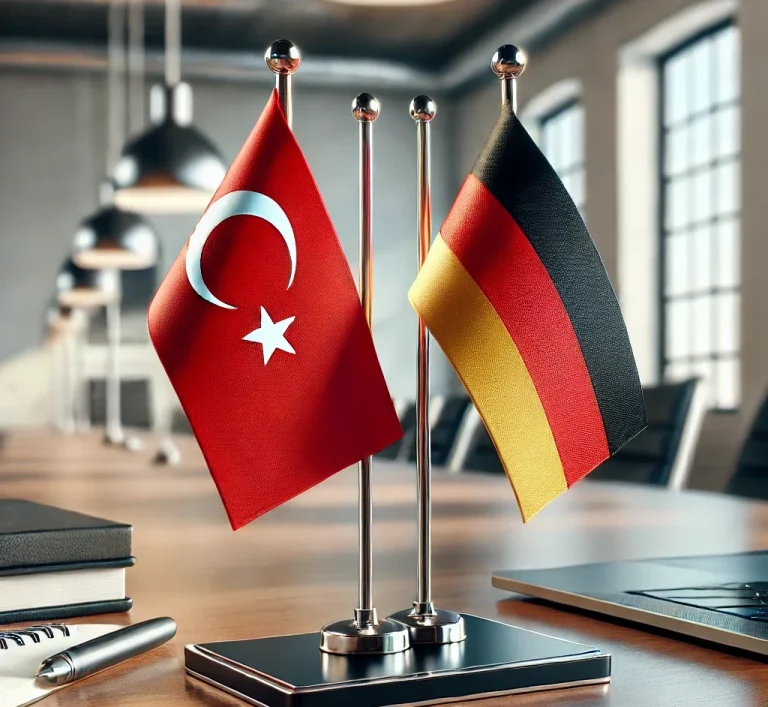 Türkische und deutsche Flaggen nebeneinander auf einem Tisch in einem modernen Raum.