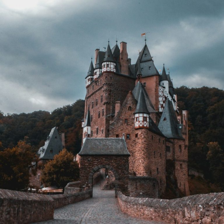 Professionelle Übersetzungs- und Dolmetsch Dienste 🇹🇷 Türkisch ⇔ Deutsch 🇩🇪 Mittelalterliche Burg mit Türmen und steinbrück, umgeben von bewaldeten Hügeln.